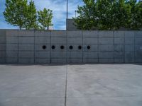 the empty parking lot in front of a wall with apartment buildings on it and a skateboarder on a ramp