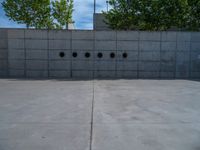 the empty parking lot in front of a wall with apartment buildings on it and a skateboarder on a ramp