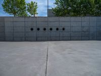 the empty parking lot in front of a wall with apartment buildings on it and a skateboarder on a ramp