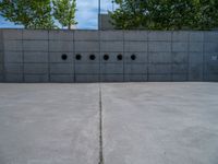 the empty parking lot in front of a wall with apartment buildings on it and a skateboarder on a ramp