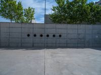 the empty parking lot in front of a wall with apartment buildings on it and a skateboarder on a ramp