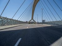 a truck driving across a bridge near a street corner near buildings and a bridge with many cables