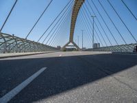 a truck driving across a bridge near a street corner near buildings and a bridge with many cables