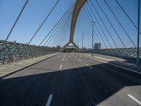 a truck driving across a bridge near a street corner near buildings and a bridge with many cables