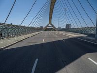 a truck driving across a bridge near a street corner near buildings and a bridge with many cables