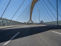 a truck driving across a bridge near a street corner near buildings and a bridge with many cables