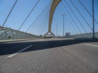 a truck driving across a bridge near a street corner near buildings and a bridge with many cables