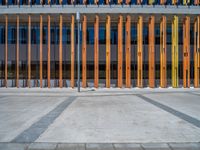 a concrete structure made into rows of orange and yellow poles are on a cement sidewalk