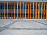 a concrete structure made into rows of orange and yellow poles are on a cement sidewalk