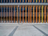 a concrete structure made into rows of orange and yellow poles are on a cement sidewalk