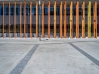 a concrete structure made into rows of orange and yellow poles are on a cement sidewalk