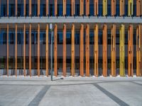 a concrete structure made into rows of orange and yellow poles are on a cement sidewalk