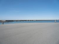 there is a long concrete walkway along the ocean front shoreline of the ocean and dock