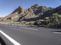 a man riding his bike down a deserted road next to the mountain range in arizona