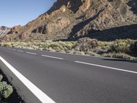 a man riding his bike down a deserted road next to the mountain range in arizona