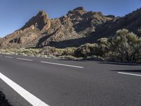 a man riding his bike down a deserted road next to the mountain range in arizona