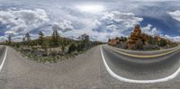 a double exposure photograph of a winding road near some mountains and a blue sky with white clouds