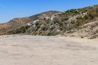 a dirt road in the hills between mountains and valleys is seen here with a clear blue sky