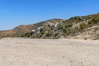 a dirt road in the hills between mountains and valleys is seen here with a clear blue sky