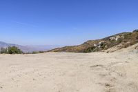 a dirt road in the hills between mountains and valleys is seen here with a clear blue sky