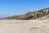 a dirt road in the hills between mountains and valleys is seen here with a clear blue sky