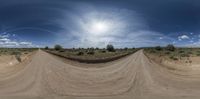 a photo of a dirt road taken from a 360 - view mirror on a sunny day