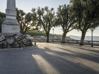 a city road going down the hill with trees on both sides of it and a stone block in the middle of the street