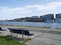 a city view with boats near some water and two park benches sitting on a cement path