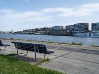 a city view with boats near some water and two park benches sitting on a cement path