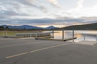 a parking lot next to a mountain in the distance with a lake behind it,