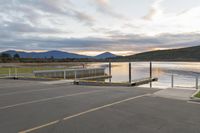 a parking lot next to a mountain in the distance with a lake behind it,