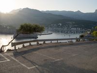 a lone bench by the ocean with mountains in the background and a tree growing out of it