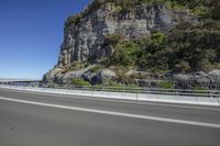 a hill with cliffs and an old road going down it, surrounded by mountains and highway railings