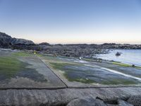 a long path between large rocks leading to the sea next to a body of water