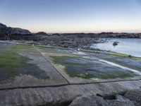 a long path between large rocks leading to the sea next to a body of water