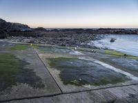 a long path between large rocks leading to the sea next to a body of water