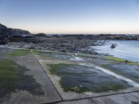 a long path between large rocks leading to the sea next to a body of water