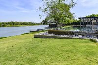 a very pretty grassy area by the water in a big backyard of an older house