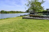 a very pretty grassy area by the water in a big backyard of an older house