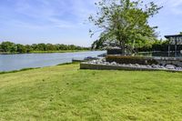 a very pretty grassy area by the water in a big backyard of an older house