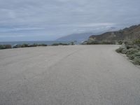 a man stands alone in front of the ocean and beach near his car parking lot