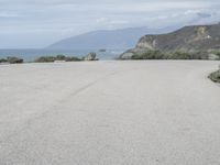 a man stands alone in front of the ocean and beach near his car parking lot