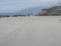 a man stands alone in front of the ocean and beach near his car parking lot