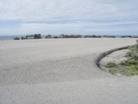 a man stands alone in front of the ocean and beach near his car parking lot