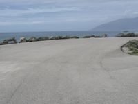 a man stands alone in front of the ocean and beach near his car parking lot