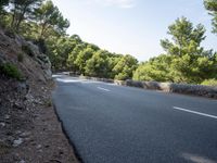 a person riding down a hill with trees on both sides of the road and hills covered in green vegetation