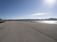 a person sitting on the beach in front of the ocean, looking at the water