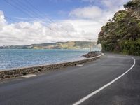 the road leads up to a cliff along the water with telephone lines strung to it