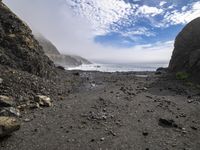 the path to the ocean has rocky beaches and rock formations in it as well as waves and clouds