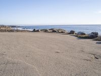 a parking lot overlooking the ocean with three large rocks in the background and two smaller rocks at the far end of the road